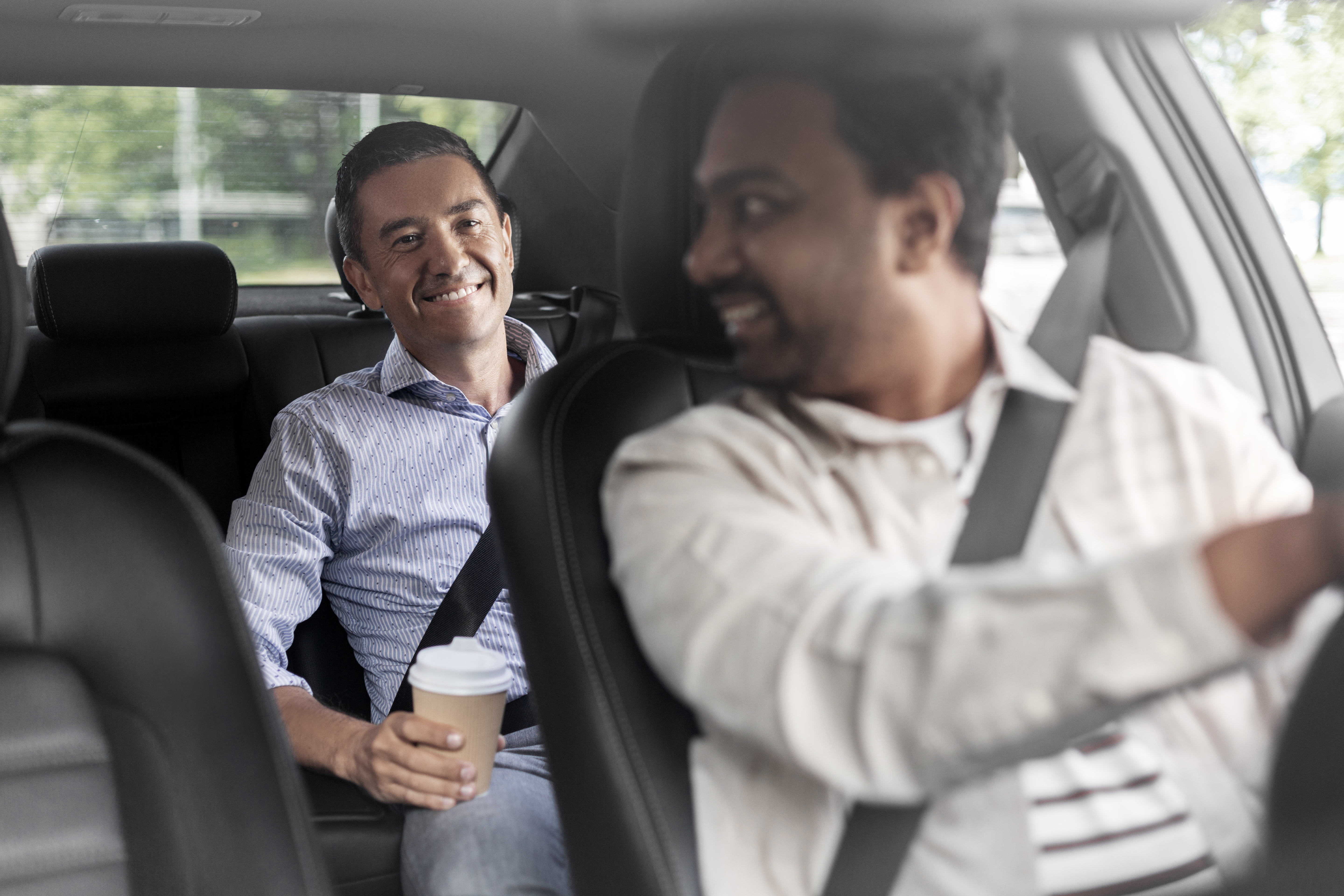male passenger with coffee talking to car driver